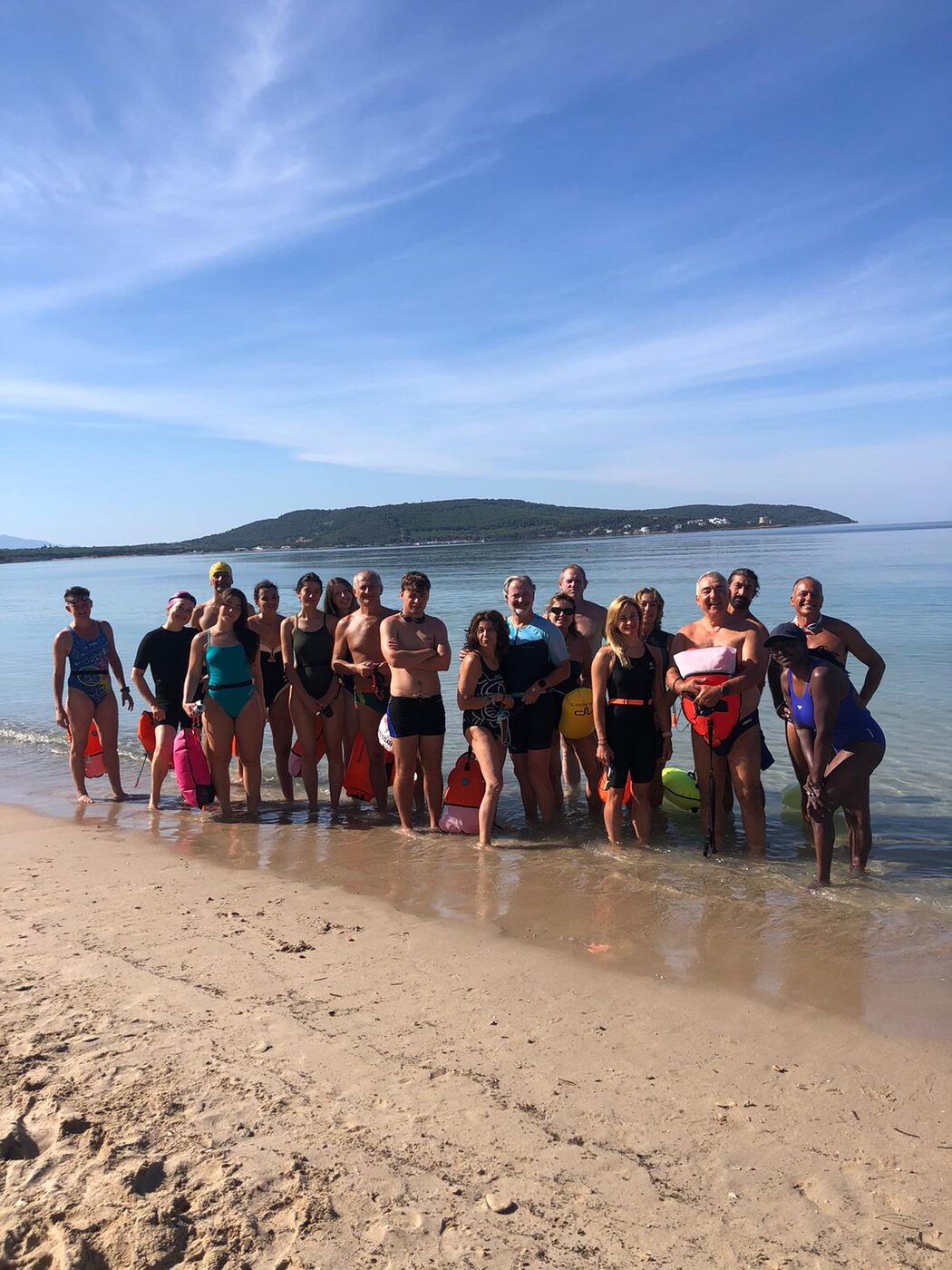 Gruppo del camp di nuoto acque libere sulla spiaggia con vista sull'isola di Tavolara, golfo di Olbia