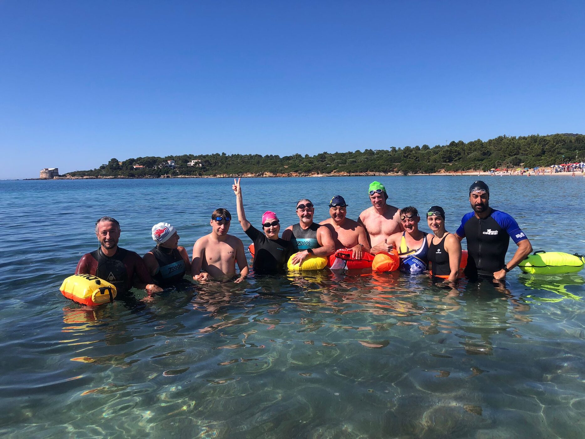 Gruppo di nuotatori con boa da traino durante un camp di nuoto in acque libere in Sardegna